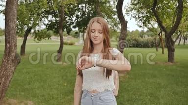 <strong>一个</strong>年轻的女孩正在公园里散步，看着她手臂上的<strong>一个</strong>智能时<strong>钟</strong>，接受脉搏测量